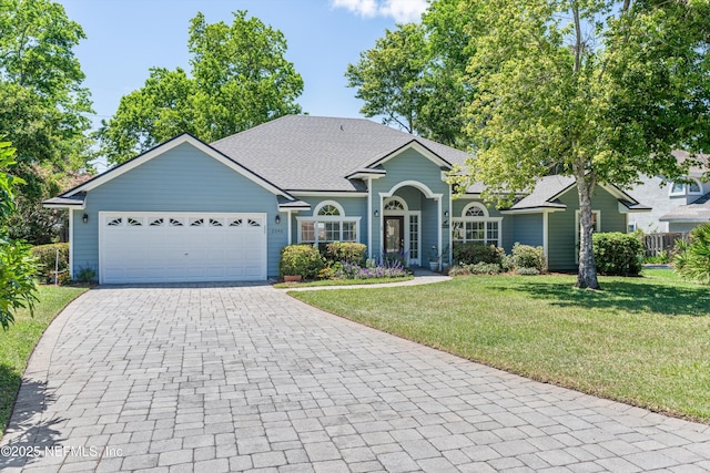 ranch-style house with roof with shingles, decorative driveway, a front yard, and a garage