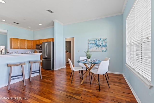 dining space featuring crown molding, a wealth of natural light, dark wood finished floors, and visible vents