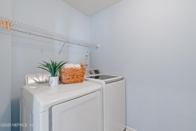 clothes washing area with laundry area, baseboards, and separate washer and dryer