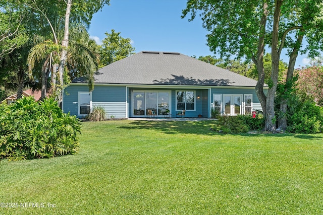 back of property with a yard and roof with shingles
