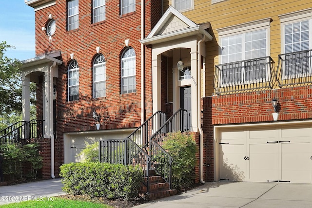 view of exterior entry featuring concrete driveway, brick siding, and a garage