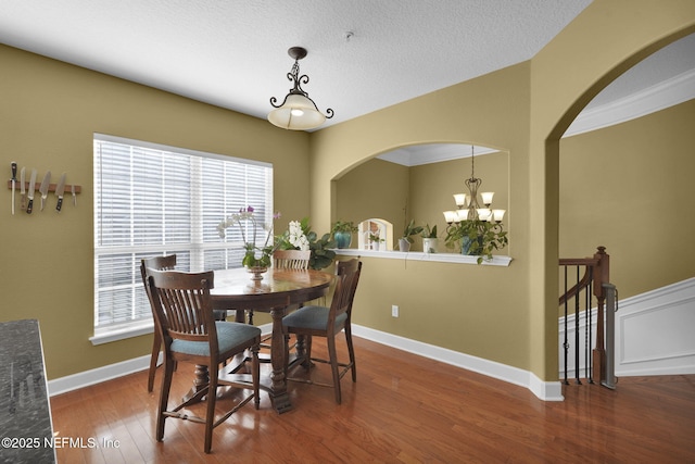 dining room with baseboards, wood finished floors, a wealth of natural light, and a notable chandelier