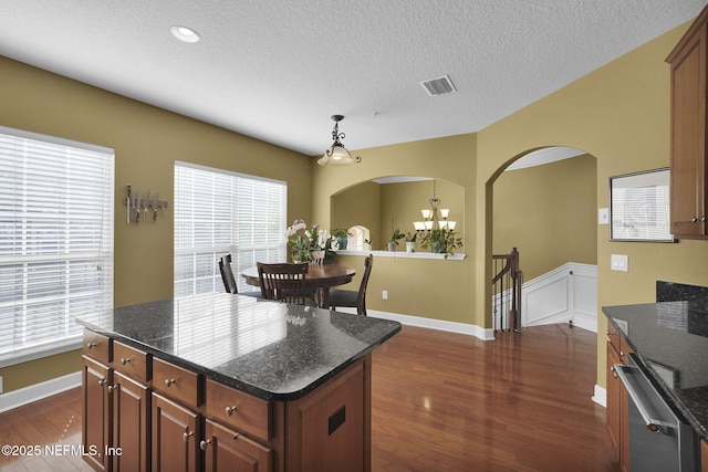 kitchen featuring arched walkways, a textured ceiling, dark wood finished floors, visible vents, and hanging light fixtures
