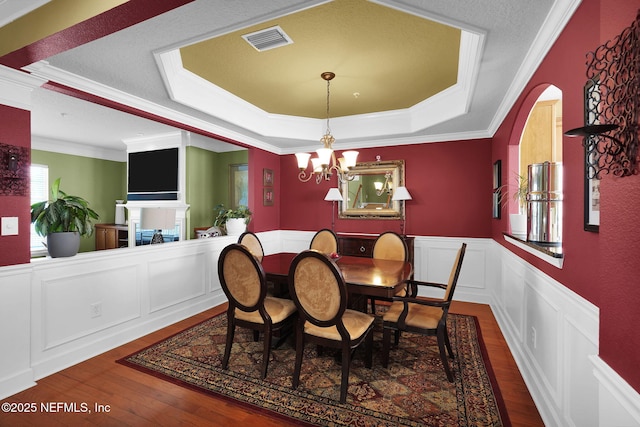 dining room with an inviting chandelier, wood finished floors, a tray ceiling, and visible vents