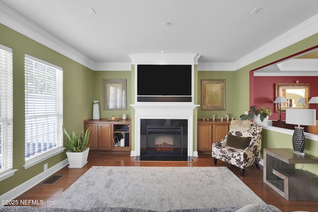 living area with a fireplace with flush hearth, a textured ceiling, visible vents, and crown molding