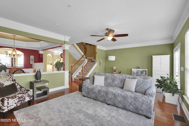 living area featuring ornamental molding, wood finished floors, visible vents, and ceiling fan with notable chandelier