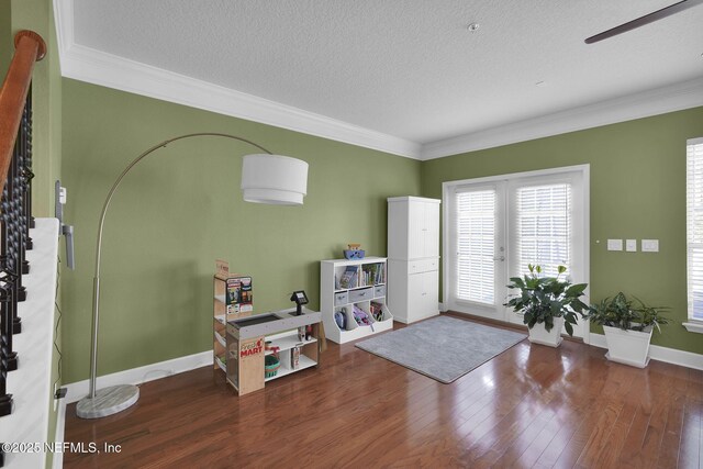 foyer entrance with wood finished floors, ornamental molding, french doors, baseboards, and a textured ceiling