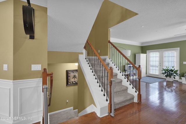 stairway with hardwood / wood-style floors, french doors, a textured ceiling, and ornamental molding