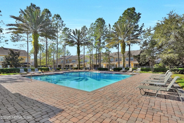 community pool featuring fence, a residential view, and a patio