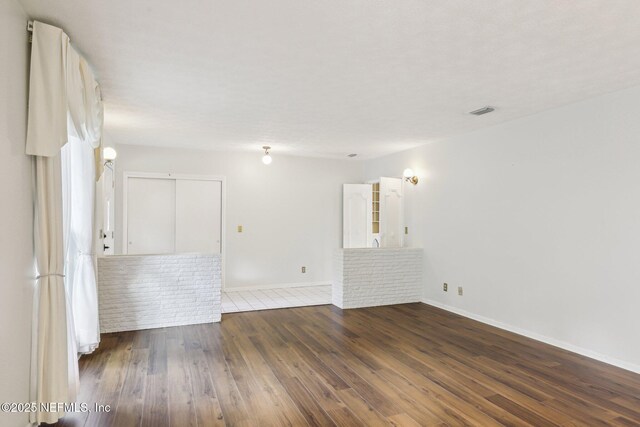 empty room featuring baseboards, dark wood finished floors, and visible vents