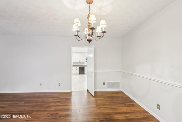 unfurnished dining area with baseboards, a notable chandelier, visible vents, and wood finished floors