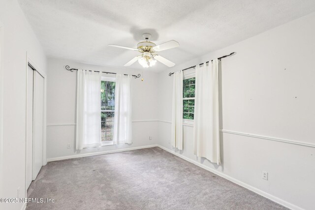empty room with carpet flooring, a ceiling fan, and baseboards