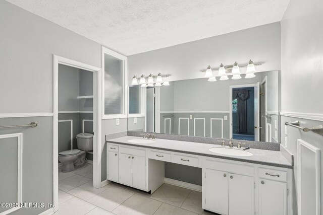 full bathroom with double vanity, toilet, a sink, and tile patterned floors