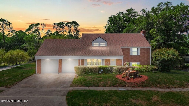 view of front facade featuring driveway, a chimney, a front yard, brick siding, and an attached garage