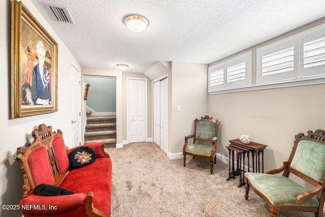 living area featuring visible vents, carpet floors, baseboards, stairway, and a textured ceiling