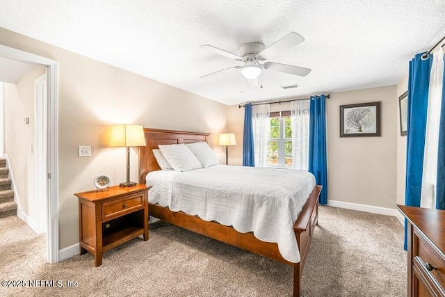 bedroom with a ceiling fan, a textured ceiling, visible vents, baseboards, and light carpet