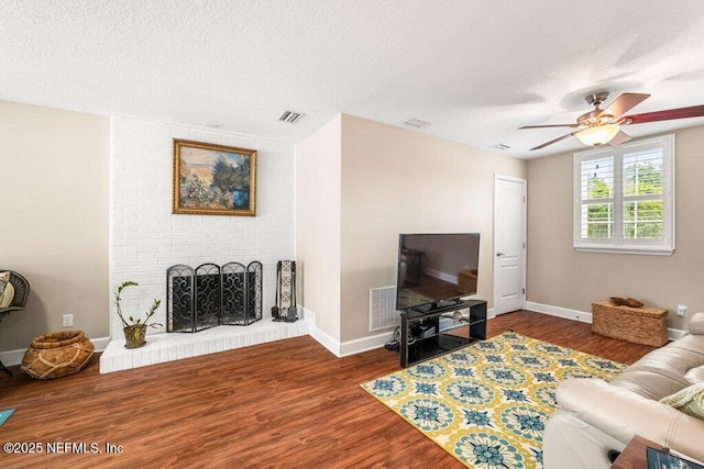 living area featuring visible vents, a textured ceiling, ceiling fan, and wood finished floors