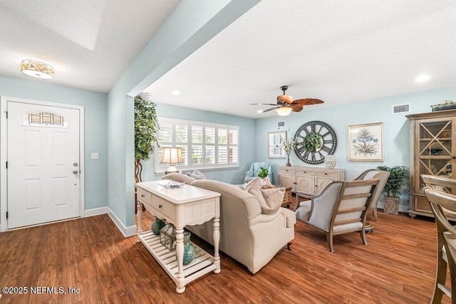 living area with visible vents, a textured ceiling, and wood finished floors