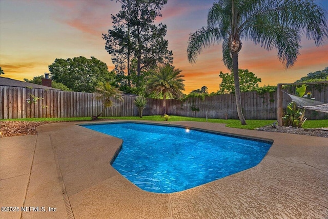 pool at dusk with a patio, a fenced in pool, and a fenced backyard