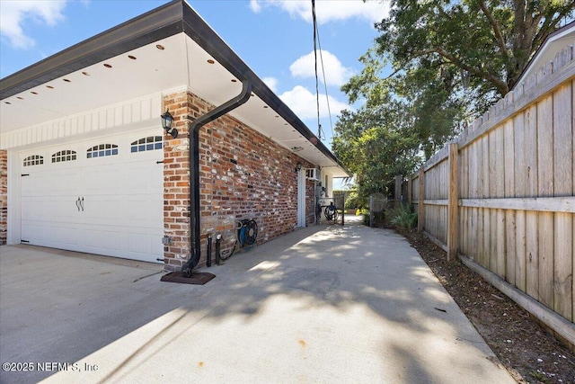 view of property exterior featuring fence, a garage, and brick siding