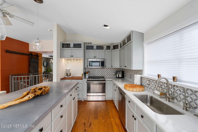 2740 Loja St, Saint Augustine, FL 32084 - kitchen with decorative backsplash, a barn door, stainless steel appliances, a sink, and lofted ceiling