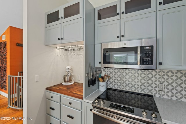 2740 Loja St, Saint Augustine, FL 32084 - kitchen featuring wood counters, glass insert cabinets, visible vents, backsplash, and appliances with stainless steel finishes