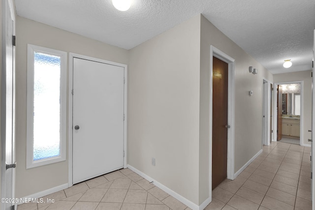 foyer with baseboards, a textured ceiling, and light tile patterned floors
