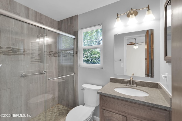 full bathroom featuring ceiling fan, toilet, vanity, and a stall shower