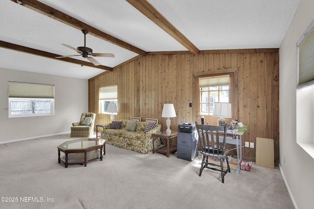 living area with a ceiling fan, vaulted ceiling with beams, wooden walls, and carpet