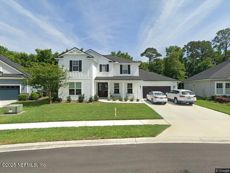 modern inspired farmhouse with a front lawn, driveway, a garage, and board and batten siding