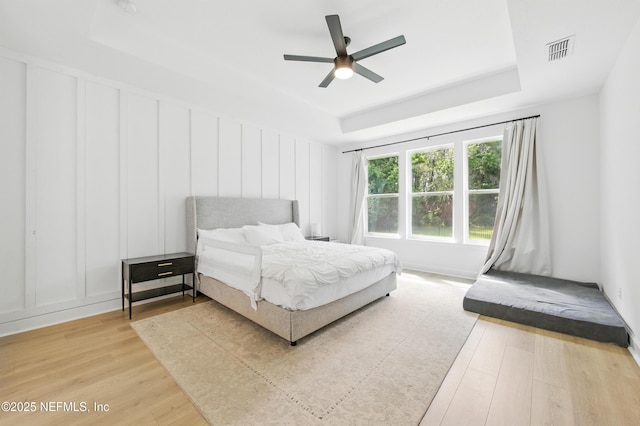 177 Windwalker Dr, Saint Augustine, FL 32092 - bedroom featuring a decorative wall, light wood finished floors, a tray ceiling, and a ceiling fan