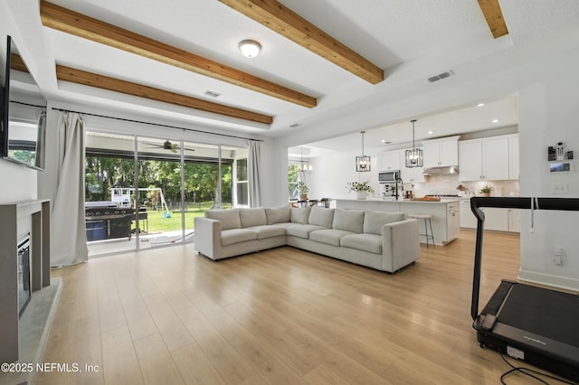 177 Windwalker Dr, Saint Augustine, FL 32092 - living room with beamed ceiling, light wood-style flooring, recessed lighting, a glass covered fireplace, and ceiling fan