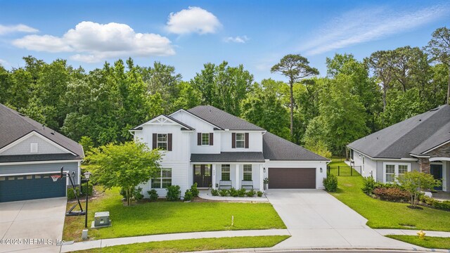 177 Windwalker Dr, Saint Augustine, FL 32092 - modern farmhouse featuring concrete driveway, a front lawn, an attached garage, board and batten siding, and roof with shingles