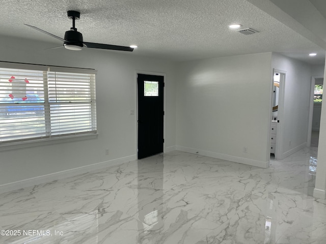 interior space with marble finish floor, baseboards, a ceiling fan, and a textured ceiling