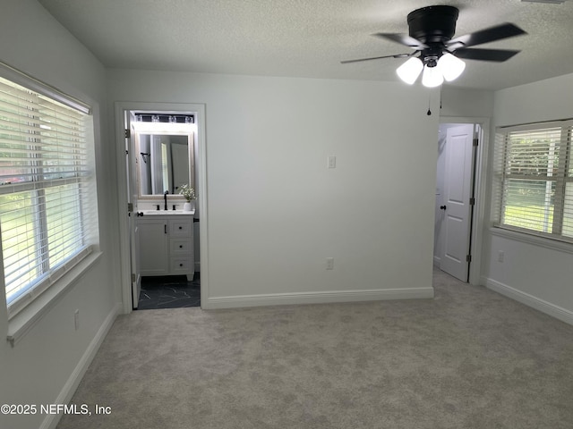 unfurnished bedroom with baseboards, carpet floors, a textured ceiling, and connected bathroom