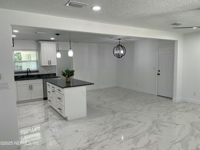kitchen featuring a textured ceiling, visible vents, marble finish floor, and a sink