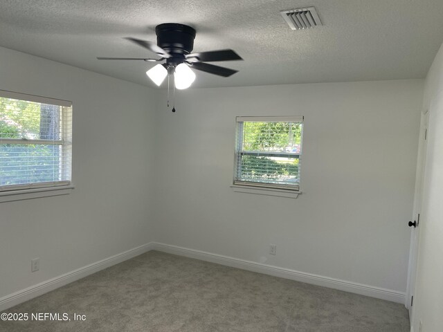 unfurnished room with a textured ceiling, baseboards, visible vents, a ceiling fan, and carpet floors