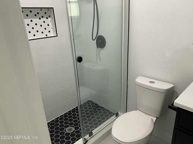bathroom with a shower stall, toilet, and vanity