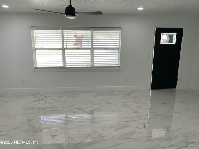 interior space with a textured ceiling, baseboards, recessed lighting, marble finish floor, and ceiling fan