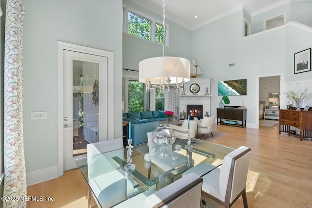 36 Preserve Island Cir, Ponte Vedra Beach, FL 32082 - dining room with a high ceiling, light wood-type flooring, a lit fireplace, baseboards, and ornamental molding