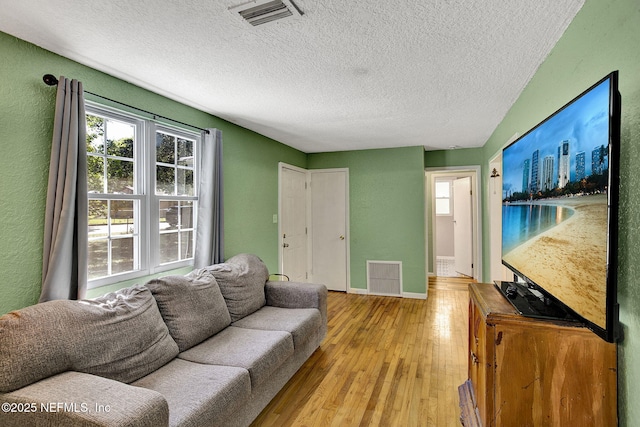 living room with a wealth of natural light, visible vents, and light wood-style flooring