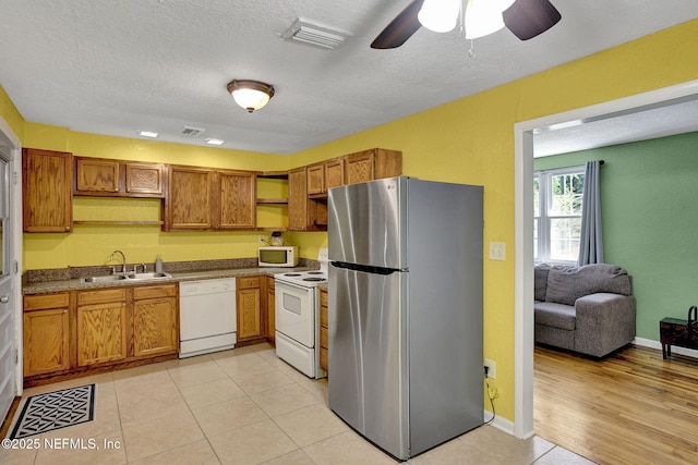 kitchen with brown cabinets, open shelves, a sink, and white appliances