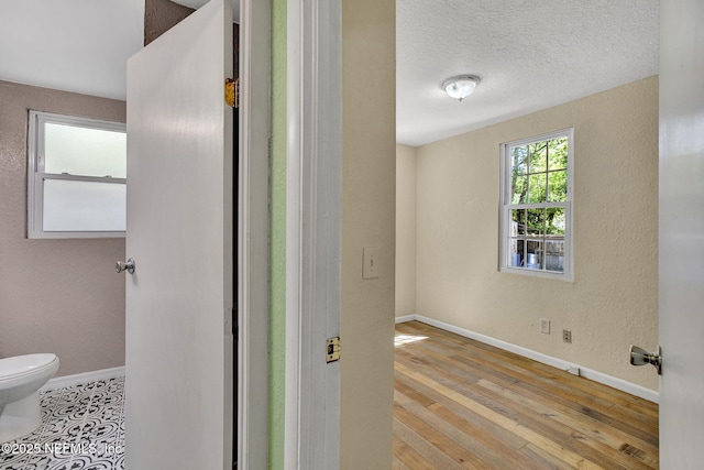 bathroom featuring wood-type flooring, toilet, a textured ceiling, and baseboards