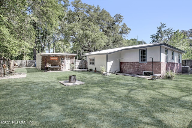 back of house with brick siding, a yard, a fenced backyard, and central AC unit