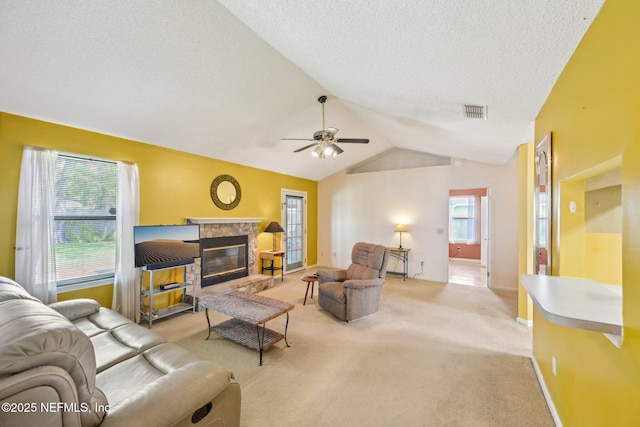 living area with vaulted ceiling, light carpet, ceiling fan, visible vents, and a textured ceiling