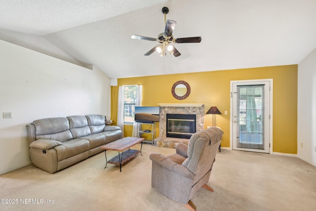 carpeted living room with baseboards, ceiling fan, a fireplace, and vaulted ceiling