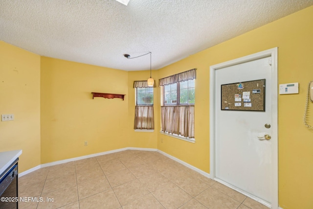 unfurnished dining area featuring light tile patterned floors, a textured ceiling, and baseboards