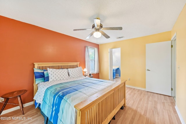 bedroom with a ceiling fan, visible vents, wood finished floors, and baseboards