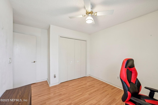unfurnished office with a textured ceiling, ceiling fan, wood finished floors, and baseboards