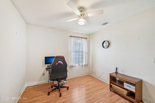 home office with ceiling fan, visible vents, baseboards, a textured ceiling, and wood finished floors